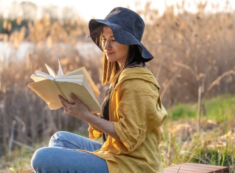 Stylish girl with a book in her hands reads at sunset.